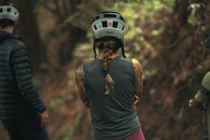 female mountain biker in a tank and helmet with her back turned to the camera