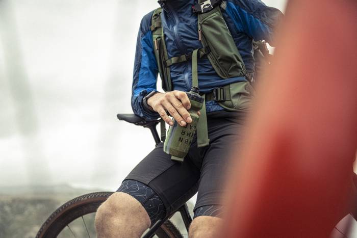 gravel biker holding water bottle, resting and leaning against saddle