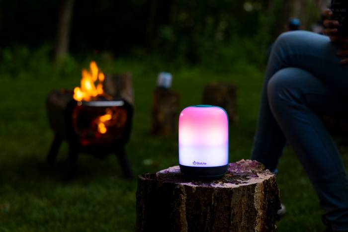 BioLite AlpenGlow Lantern Sitting On a Log By a Campfire FirePit