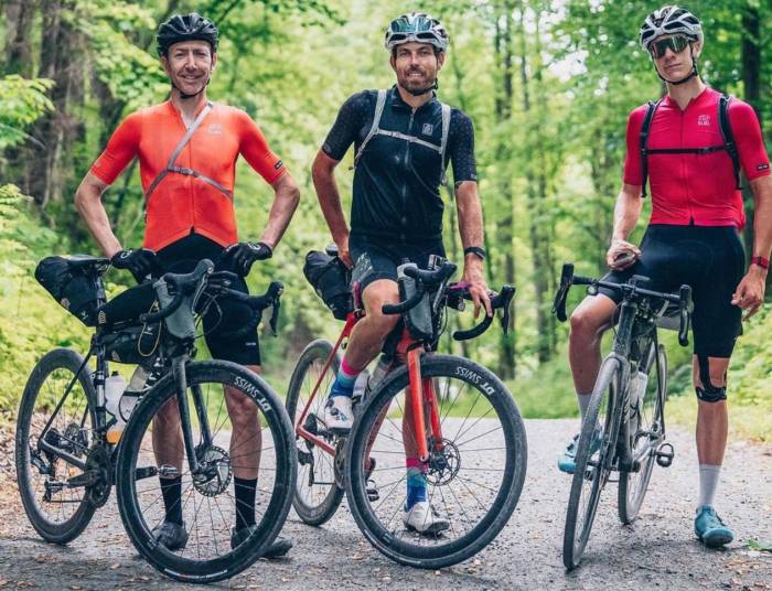 3 cyclists on their bikes paused in a roadway with their bikepacking gear