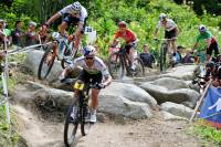 several mountain bike athletes racing down rocky course at a UCI World Cup