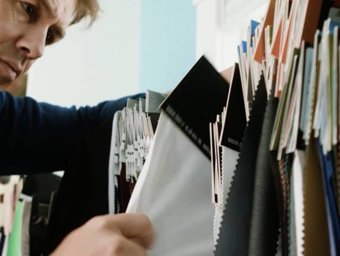 man looking intently at apparel fabric swatches