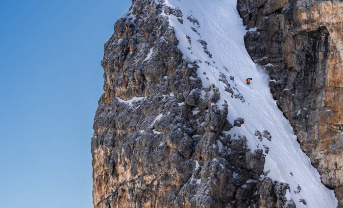 freeskier on narrow gully of snow in verbier, switzerland