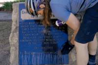 a female cyclist washing off a momument to a historic stagecoach driver