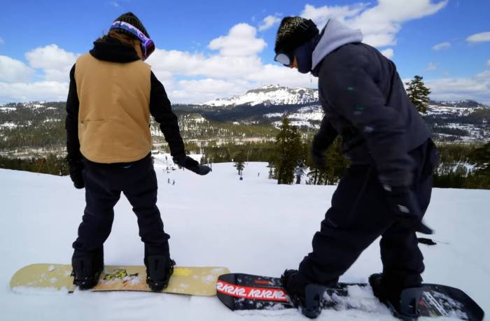 tim and hannah eddy on snowboards at the top of a run about to high five