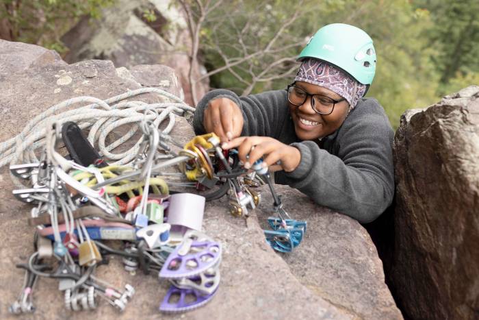 Partner in adventure grant recipient Zorbari Nwidor practicing anchor building by fitting different sized cams into a rock.