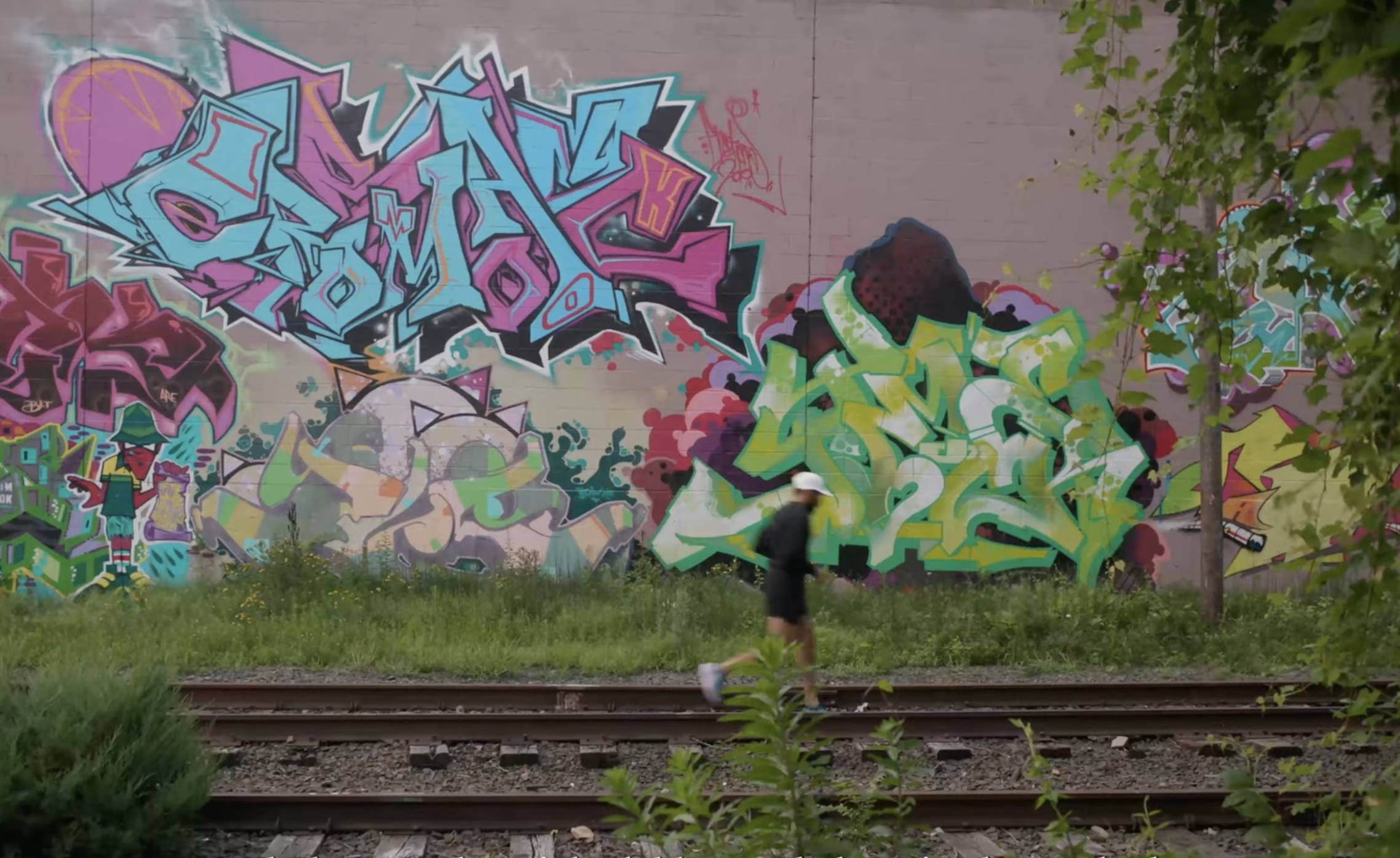 HOKA athlete Jorge Moreno running past a mural near train tracks