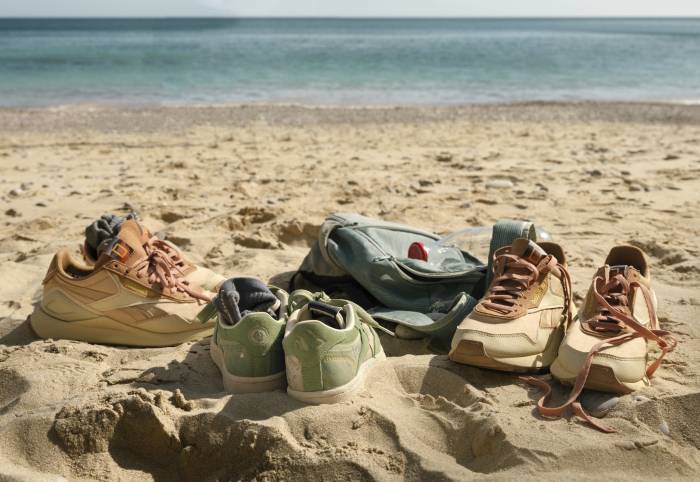 three pairs of Reebok Nat Geo shoes resting in the sand