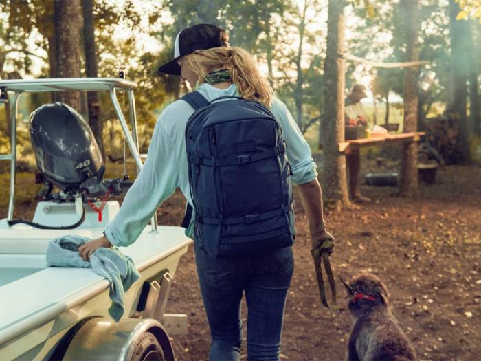 Woman walking dog near boat while wearing YETI Crossover 35L Travel Backpack
