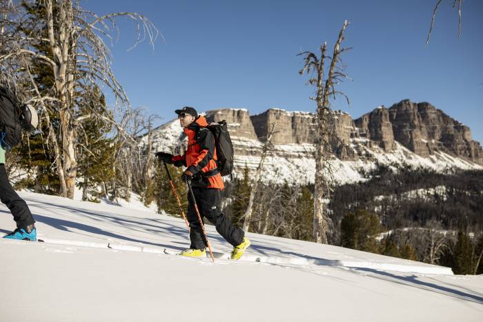 person skinning up a hill with skis and mountain gear
