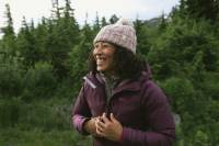 REI Launches 'Navigate' to Fund Small Business Owners of Color: Apply Now! Black woman in a purple pink jacket and pom beanie hiking outdoors