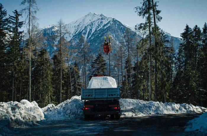 a man does a flip on skis into the back of a truck