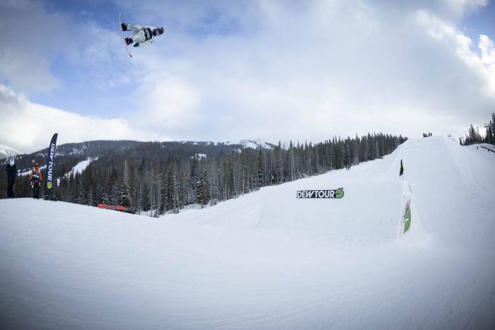 Julia Marino doing a flip high in the air off a jump section on her snowboarding at the Dew Tour 2021 competition