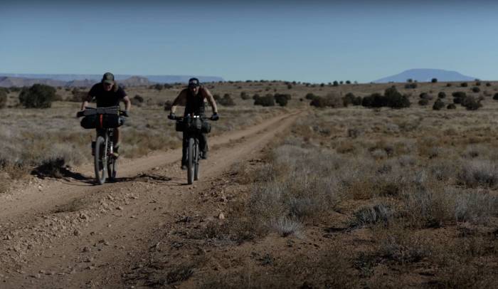 two people on bikes bikepacking a flat gravel trail in Utah