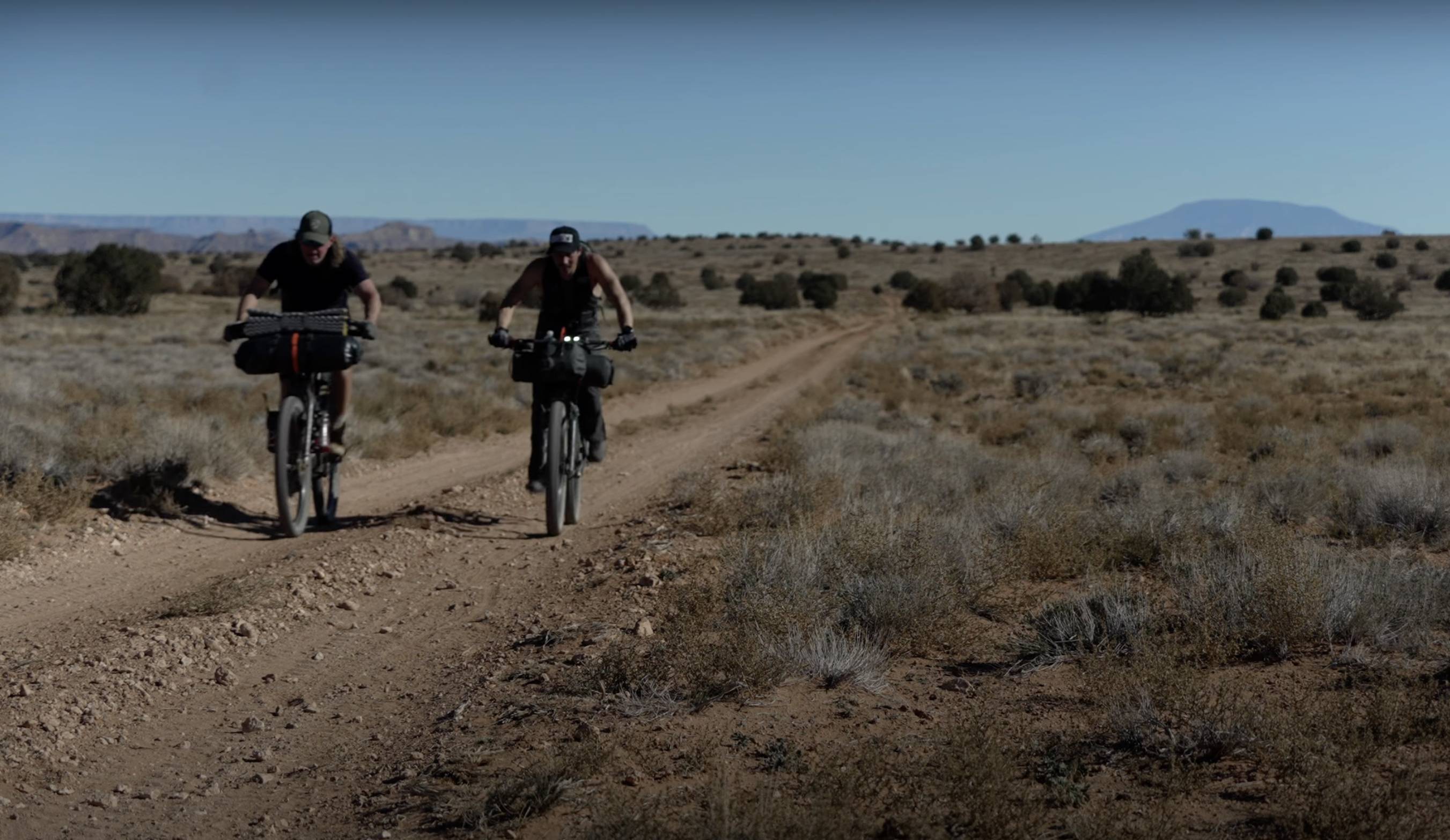 two people on bikes bikepacking a flat gravel trail in Utah