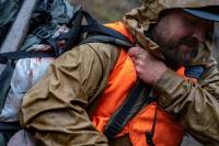 Vista Outdoor Acquires Stone Glacier, Adds to Its Arsenal of Hunting Brands a man in a rain jacket and orange vest with a heavy hunting pack over his shoulder