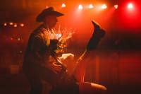 Skier Combines Winter Sports, Western Dance in 'Boots Over Brim' man and woman in cowboy hats and boots dancing under a red-lit stage