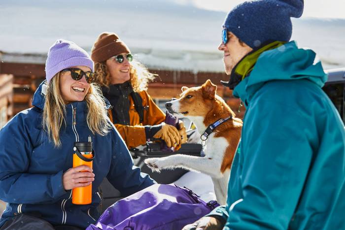 Three people and a dog enjoying the snow holding Hydro Flask Bottles