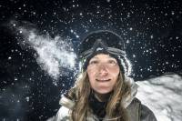 A Pro Snowboarder Talks Mindfulness in Competition, in the Backcountry, and Beyond Jamie Anderson snowboarder standing in a winter jacket in goggles against a dark snowy backdrop