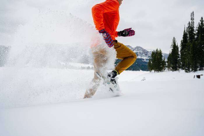 person in red fleece running on snowshoes through the snow