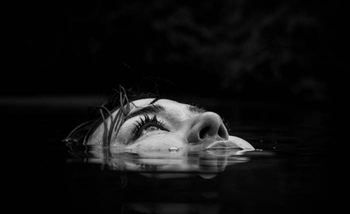 jess kimura floating her face near the surface of dark water