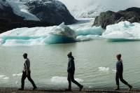 Three people walking along the edge of icy waters
