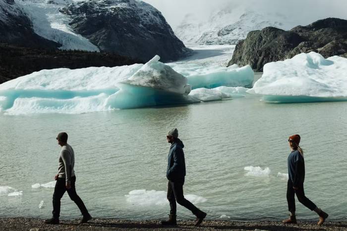 Three people walking along the edge of icy waters