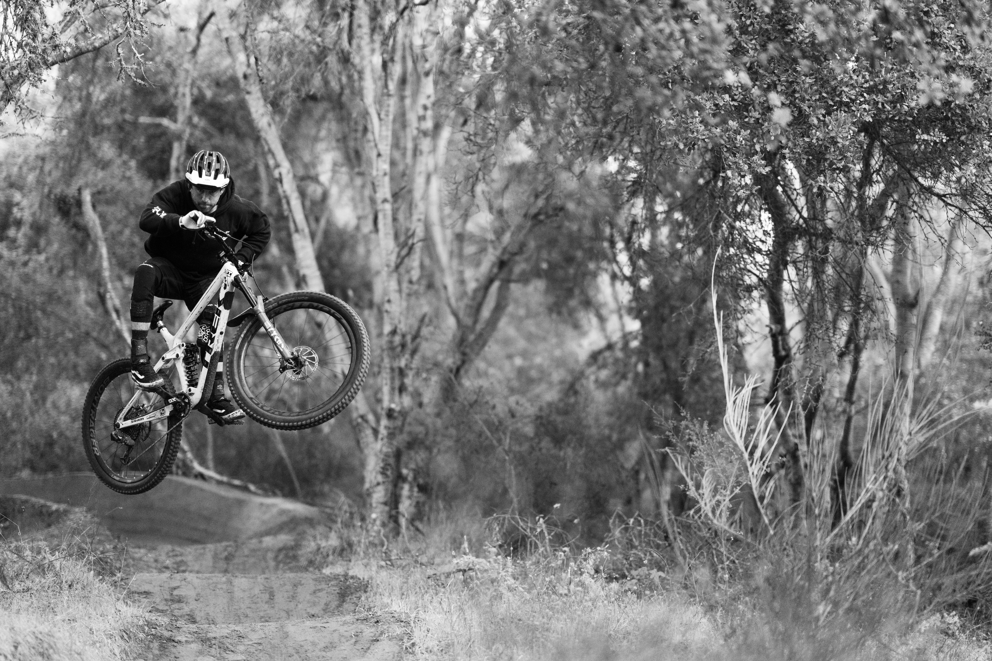 black and white photo of ryan howard mid-air on a mountain bike