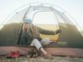 Gear Bargains: Save on BUFF, ALPS Mountaineering, Mountainsmith, and More Woman sitting in a stoic tent wearing hiking gear and camping