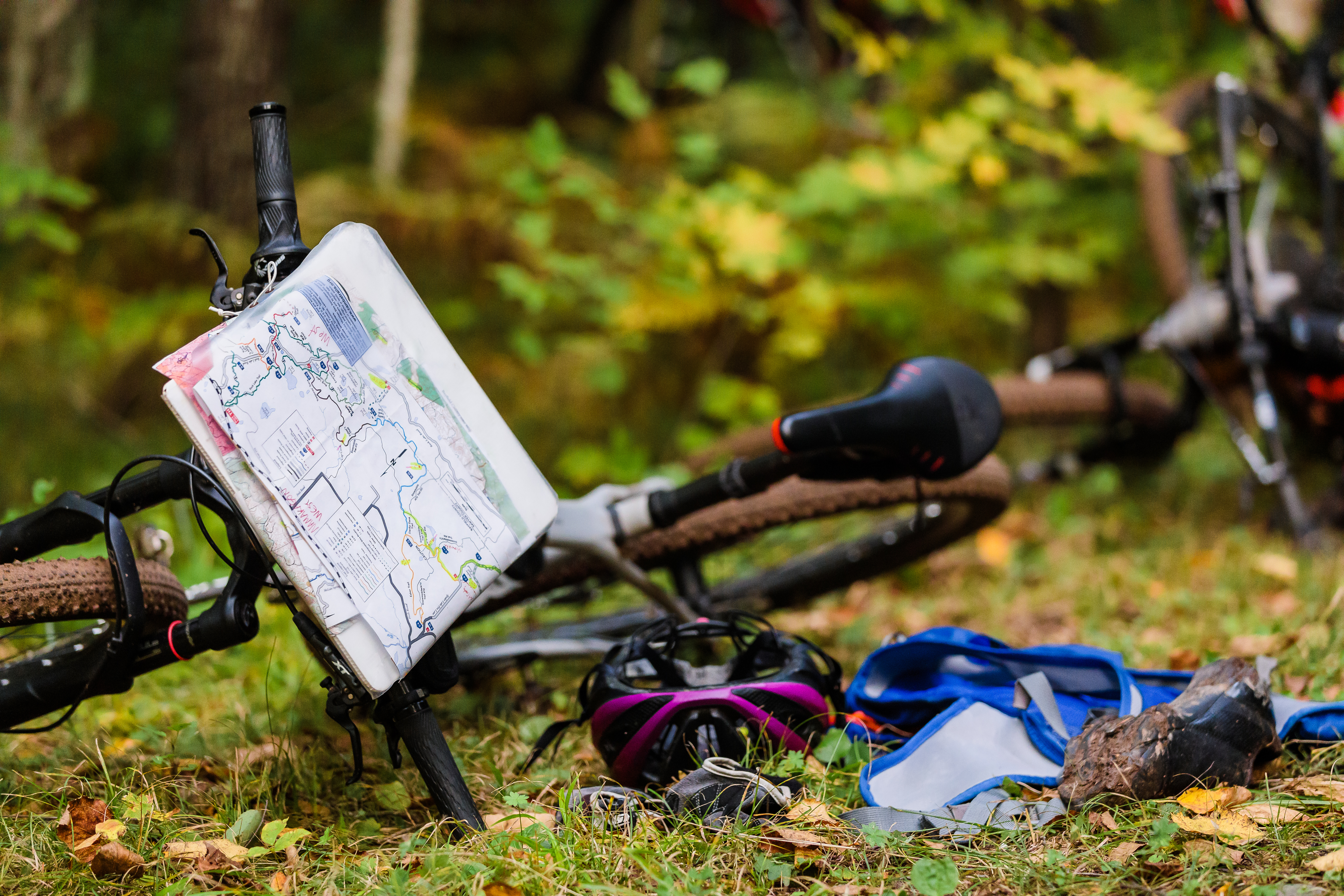 Mountain bike laying on the ground with a helmet and a map ready to go.