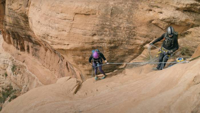 two climbers rappeling down a sloped rock in Sedona, Arizona