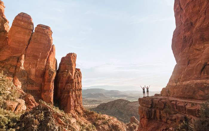 Two hikers overlooking some big rocks and a canyon.