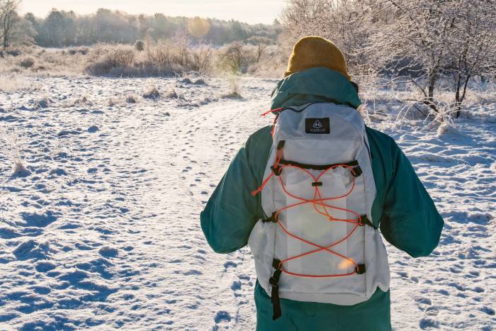a person in a turquoise jacket wearing a Hyperlite Daybreak pack in the snow.