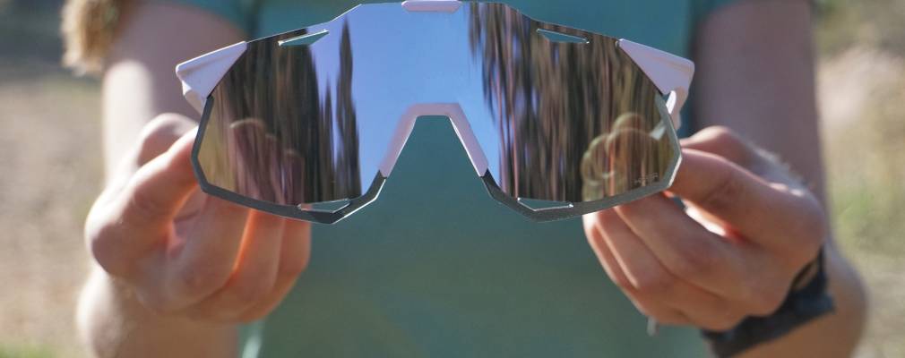Gear We Love: Our Favorite Gear This May a woman holding up the 100% hypercraft xs sunglasses in a soft lavender tint