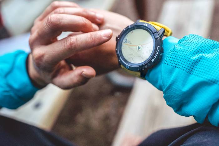 person holding their arm out to check their Coros VERTIX 2 GPS watch while wearing a blue jacket