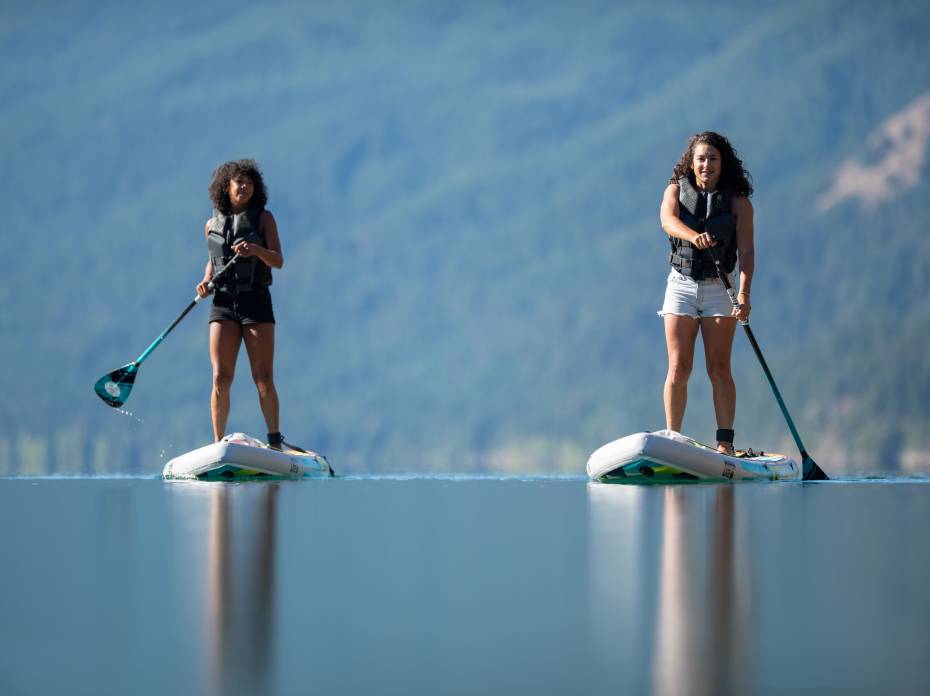 Hyperlite Wakeboards Releases Affordable 'Elevation' iSUP for Beginners two women paddling on an alpine lake using the Hyperlite HO Elevation iSUP.x