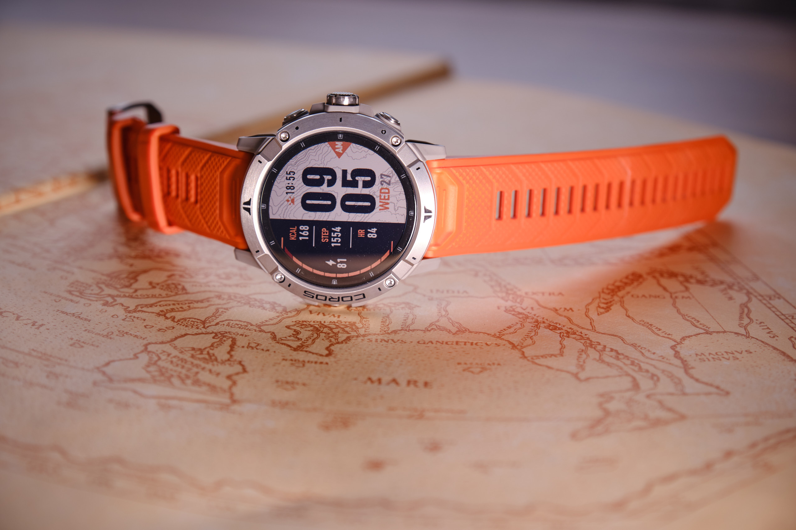 coros VERTIX 2 GPS watch with an orange band laying on top of a map