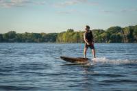 The Price of Pure Joy is $11,000: YuJet Electric Jetboard Review Man Riding the YuJet Electric Jetboard Surfboard on the Lake During a Glorious Sunset