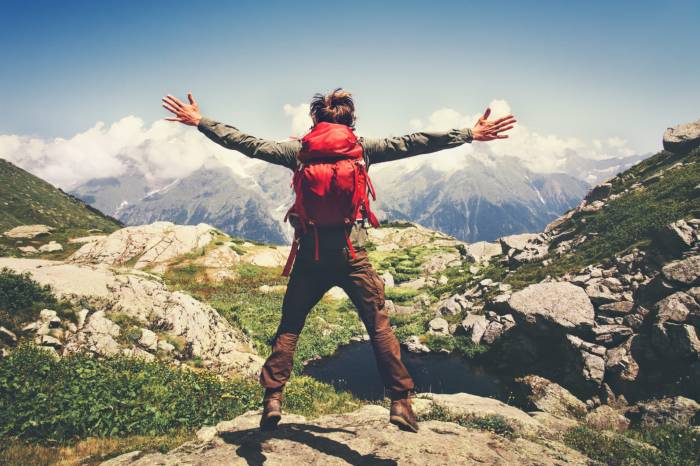 Hiker with backpack jumps on a mountain pass.