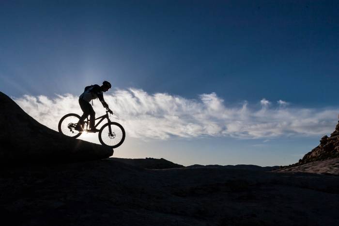 a man rides a bicycle along a ridgeline
