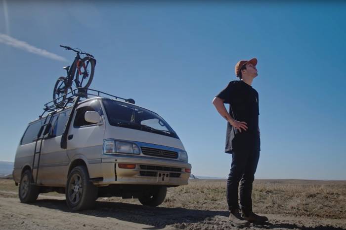 a man stands next to a van out in the desert