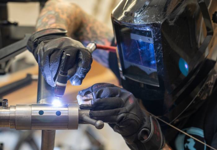 a person in a protective face mask welding on the frame of a bike