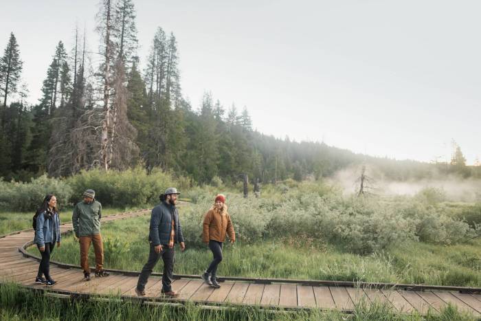 four people walking on a boardwalk during the fall