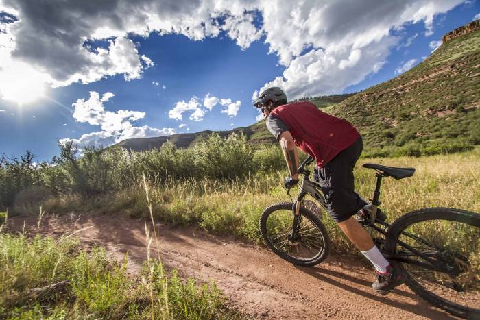 a man in a red jersey rides a mountain bike on a trail in colorado