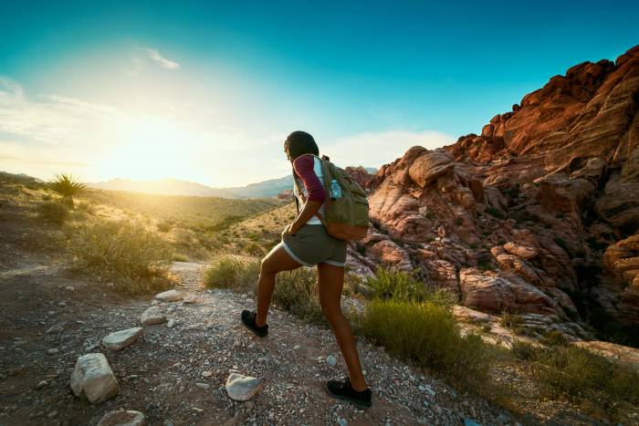 a Black woman hikes along a rocky trail