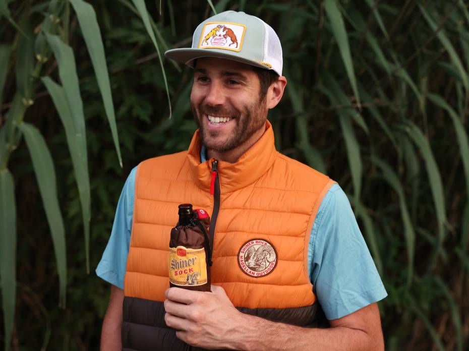 This Gear & Beer Collab Stands Out for the Money (and Style) Man wearing Shiner Bock x Magellan puffy vest and hat