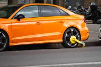 The Best Car Anti-Theft Devices Wheel lock clamp (tire boot) on rear wheel of orange car parked in the city