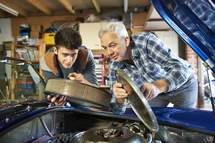 father and son working together on a classic car in a garage
