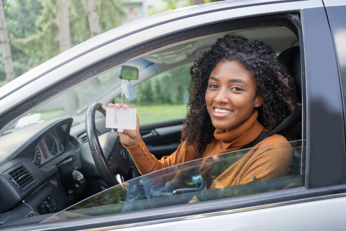 woman in car showing her driver's license