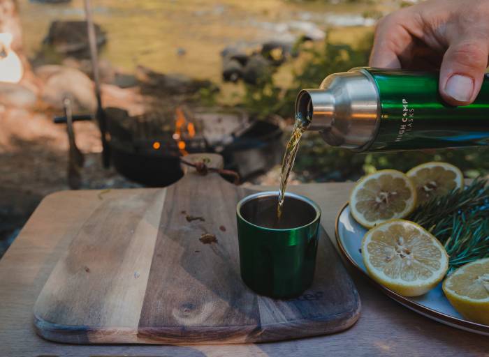 A hand pouring cocktails from a high camp flask